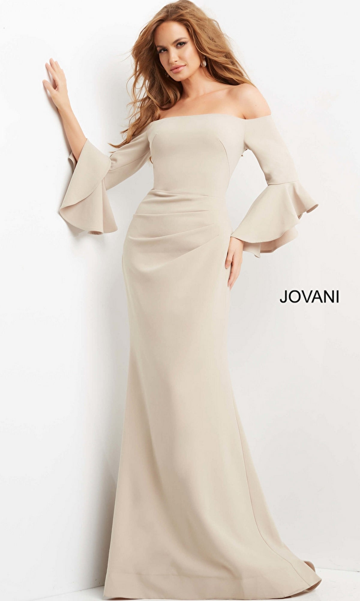 A woman wears the Jovani 07065 Bell-Sleeve Designer Evening Gown, an off-the-shoulder, floor-length beige gown with flared sleeves. The Jovani brand name is displayed beside her.
